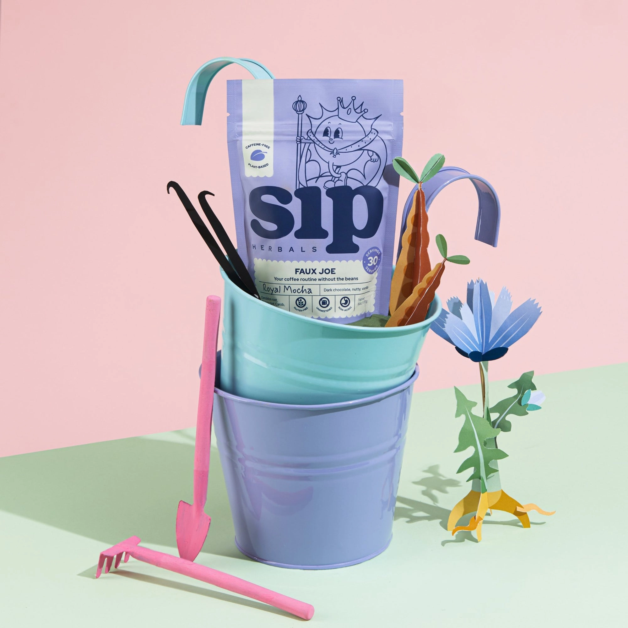 Sip Herbals bag in a blue bucket with paper flowers on a pink table