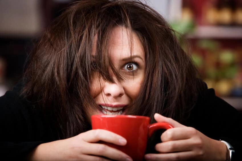 A woman with wild hair holding a red mug